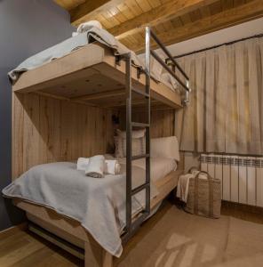 エステリ・ダネウにあるBARN THE RETREAT Apartamento premium en Esterriの二段ベッドが備わる木製の壁の客室です。