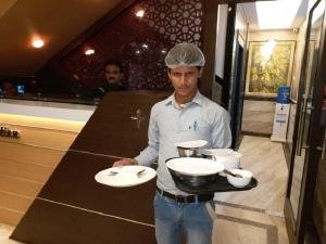 a man holding a tray with two plates and a bowl at Le Emerald Residency in Tambaram