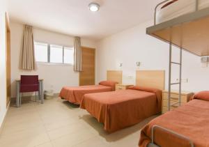 um quarto de hotel com duas camas com lençóis laranja em Albergue Inturjoven Sevilla em Sevilha