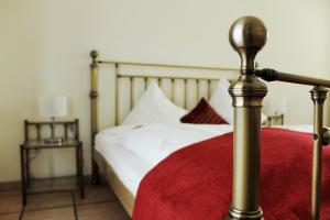 1 cama con sábanas blancas y manta roja en Akazienhof Hotel & Brauhaus, en Colonia