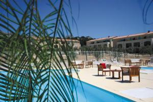 vistas a una piscina con mesas y sillas en Lagrange Vacances Le Domaine de Bourgeac en Paradou