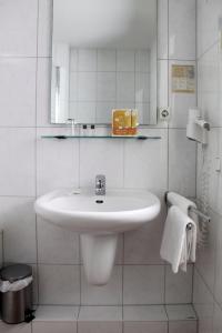 a white bathroom with a sink and a mirror at Akazienhof Hotel & Brauhaus in Cologne