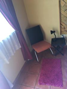 a room with a chair and a window and a rug at 1010 Clifton bnb in Centurion
