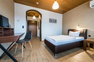Schlafzimmer mit einem Bett, einem Schreibtisch und einem Stuhl in der Unterkunft Hotel Es Lämmche in Breuberg