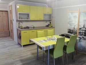 a kitchen with yellow cabinets and a table with green chairs at Michałowice Noclegi u Anety in Michałowice