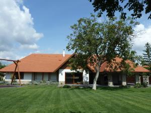 una casa con un árbol en el patio en Villa Holiday, en Poroszló