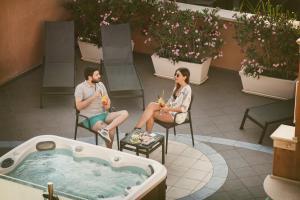 two people sitting in chairs next to a hot tub at Artemis Hotel in Cefalù