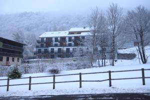 a building with snow on the ground next to a fence at A1 - Résidence La Montille in Le Mont-Dore