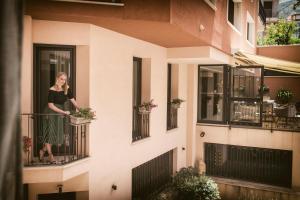 a woman standing on a balcony of a building at Artemis Hotel in Cefalù