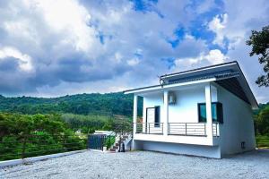 une petite maison blanche avec une colline en arrière-plan dans l'établissement White House Langkawi, à Kuah