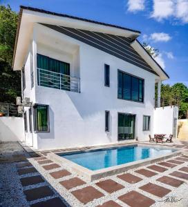 a villa with a swimming pool in front of a house at White House Langkawi in Kuah