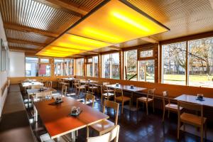 ein Restaurant mit Tischen, Stühlen und Fenstern in der Unterkunft Jugendherberge Garmisch-Partenkirchen in Garmisch-Partenkirchen