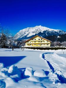 a snow covered field with a house and a mountain at Alpen Experience Hotel in Gröbming