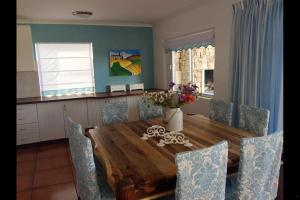 a dining room table with chairs and a vase of flowers on it at Villa Amore in Paternoster