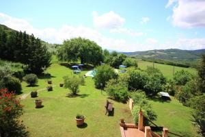 um jardim com bancos e árvores num campo em Podere Il Tigliolo em Castiglione dʼOrcia