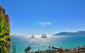 two boats in the water with a beach and buildings at MyHome Riviera - Cannes Sea View Apartment Rentals in Cannes