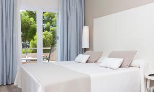 a white bedroom with a large white bed and a window at Canyelles Platja in Roses