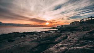 a sunset over the ocean with a rocky shore at 28 Peter in Sliema