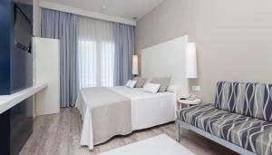 a white bedroom with a bed and a couch at Canyelles Platja in Roses