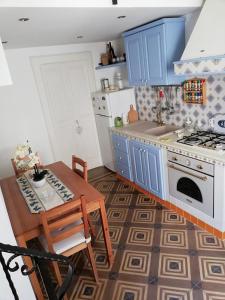 - une cuisine avec des placards bleus, une table et une cuisinière dans l'établissement Casa in corte, à Matino