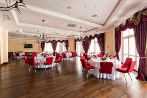 a banquet hall with white tables and red chairs at Клубный отель "Завидово" in Zavidovo