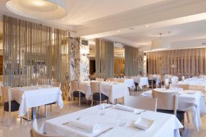 a restaurant with white tables and white chairs at Canyelles Platja in Roses