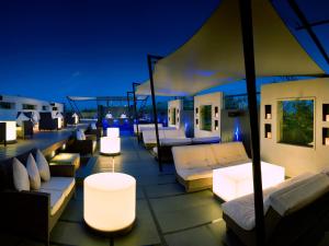 a rooftop patio with couches and tables and lights at The Lalit Ashok in Bangalore
