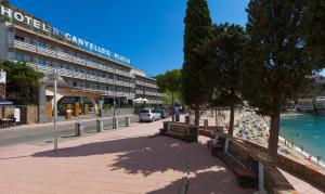 a beach with benches and a building next to the water at Canyelles Platja in Roses