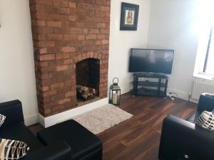 a living room with a brick fireplace and a television at 'Park House' in Chorley