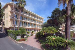 un edificio con palmeras frente a una calle en Hotel Paradiso en Sanremo