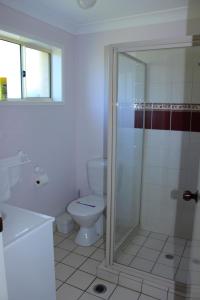 a white bathroom with a toilet and a shower at Kilcoy Gardens Motel in Kilcoy
