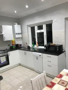 a kitchen with white cabinets and a microwave at Streatham Common Bed & Breakfast in London