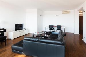 a living room with a black leather couch and a table at Skyscraper Riverview Lisbon with Indoor Pool in Lisbon