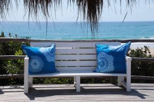 a white bench with blue pillows on the beach at Tilak Lodge in Praia do Tofo