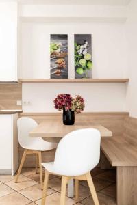 uma mesa de jantar com duas cadeiras e um vaso de flores em Pixner Apartments em Bolzano
