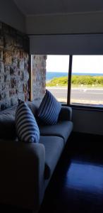a couch with two pillows in a room with a window at Normandie On Sea in Hermanus