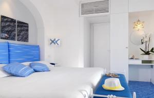 a white bedroom with blue pillows and a white bed at Relais Maresca Luxury Small Hotel & Terrace Restaurant in Capri