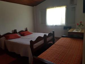 a bedroom with two beds with red pillows and a window at Casa familiar Zarza Mora in San Carlos de Bariloche