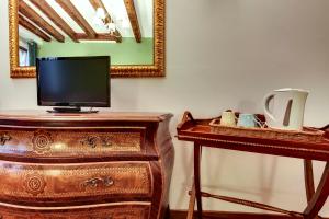 een televisie op een dressoir naast een tafel met een spiegel bij San Marco Superior Apartments in Venetië