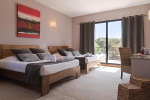 a bedroom with two beds and a large window at Hôtel Disini Montpellier Est, The Originals Relais (Relais du Silence) in Castries