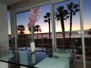 a glass table with a vase with flowers on it at Apartamento Lujo frente al Mar Centro de Malaga in Málaga