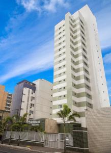 a tall white building with trees in front of it at Aquidabã Praia Hotel in Fortaleza