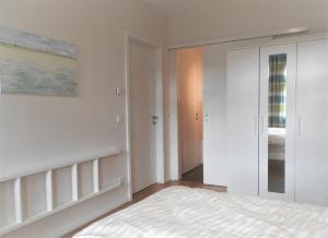 a white bedroom with a bed and a mirror at Design Apartments - "Am Schlosspark" Adults Only in Potsdam