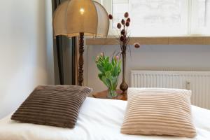 a bed with two pillows and a lamp and a vase of flowers at Traditional Apartment Starowiślna street in Krakow