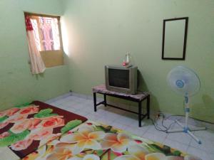 a room with a bed and a television and a fan at Setro Kariyo Homestay in Bantul