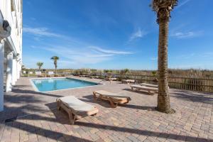 a swimming pool with two lounge chairs and a palm tree at Windy Shores II in Myrtle Beach