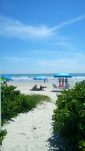 a beach with people sitting under umbrellas and the ocean at Apartamento - Pé na Areia in Itapema