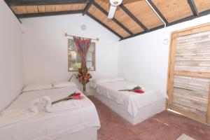 two beds in a room with white walls and a window at Casa Grande Surf in Guachaca