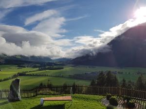 - une vue sur un champ avec une clôture et une montagne dans l'établissement Bauernhof Oberscheffau, à Neukirchen am Großvenediger