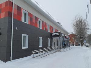 a building with a sign on it in the snow at Klukva Hostel in Syktyvkar